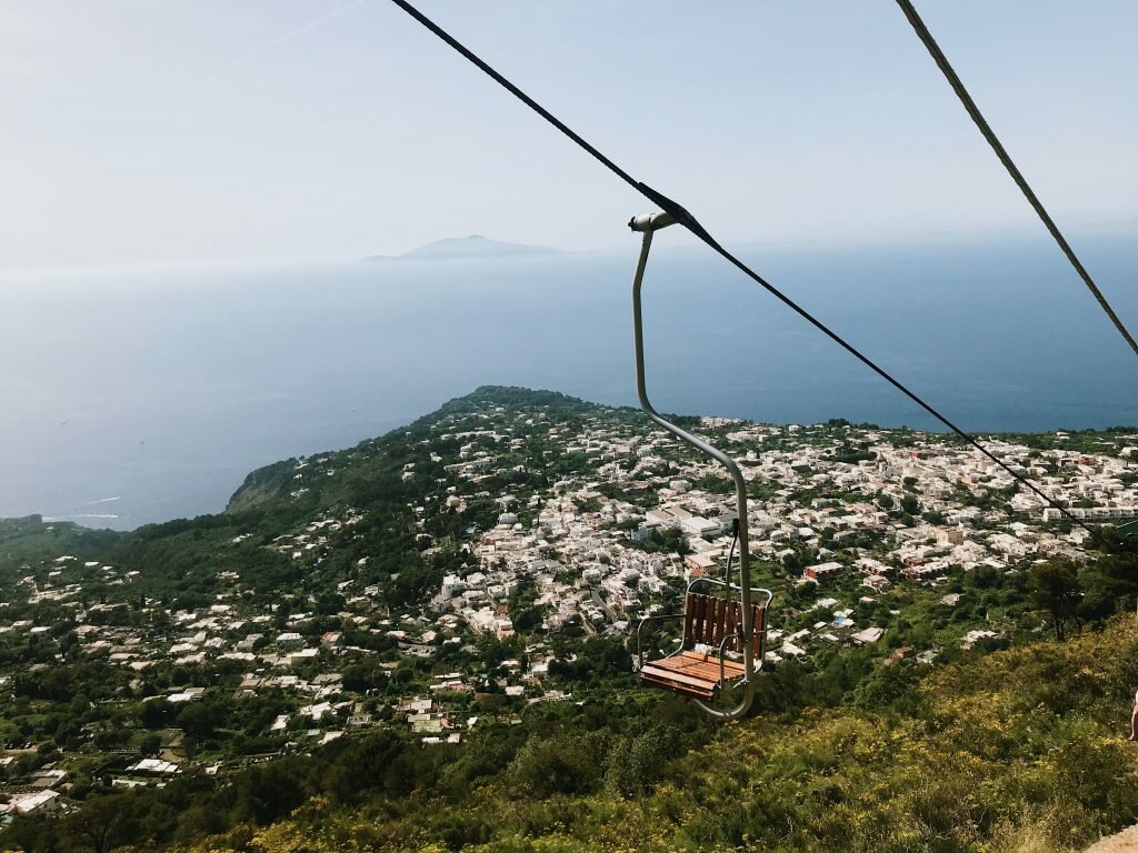 one chair lift in the foreground of mountains and oceans